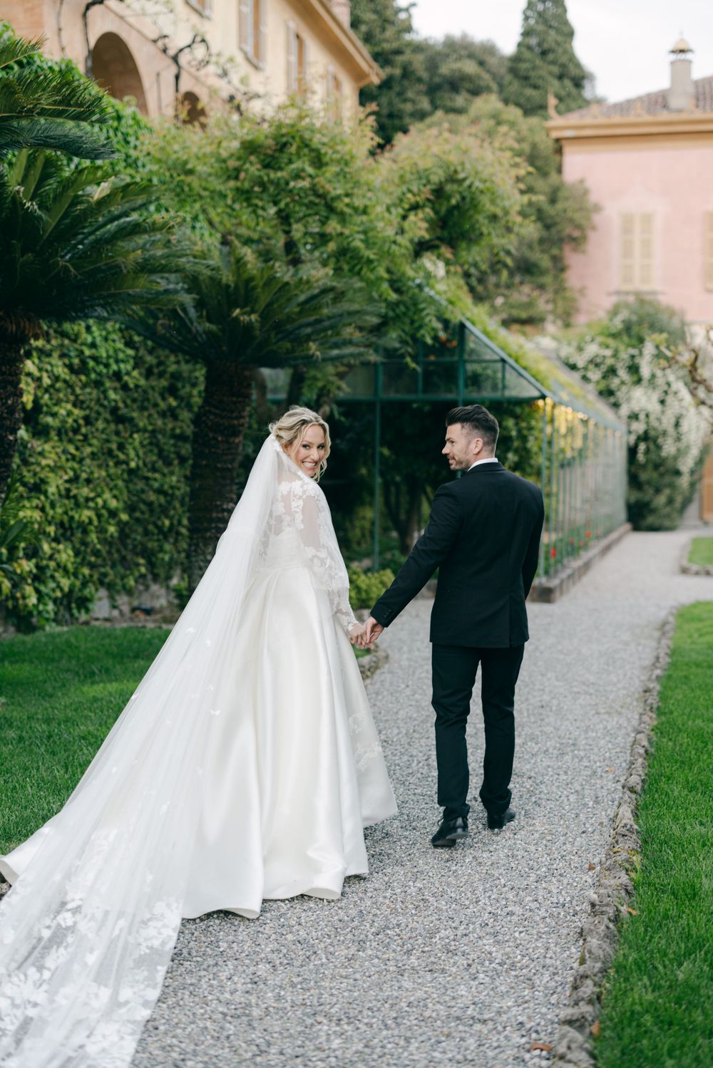 A romantic garden path scene with elegant wedding attire against lush greenery.