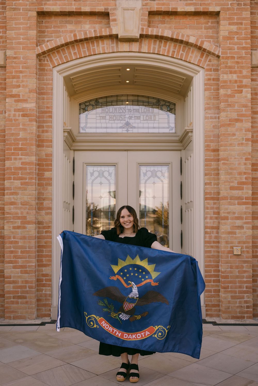 North Dakota state flag displayed in front of an elegant brick building entrance.