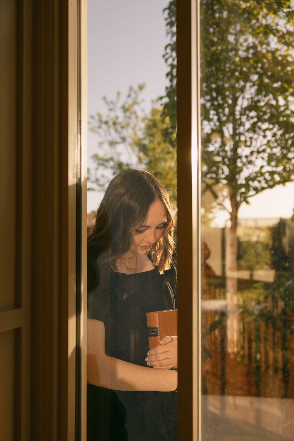 Sunlit portrait through a window frame with warm golden evening light.