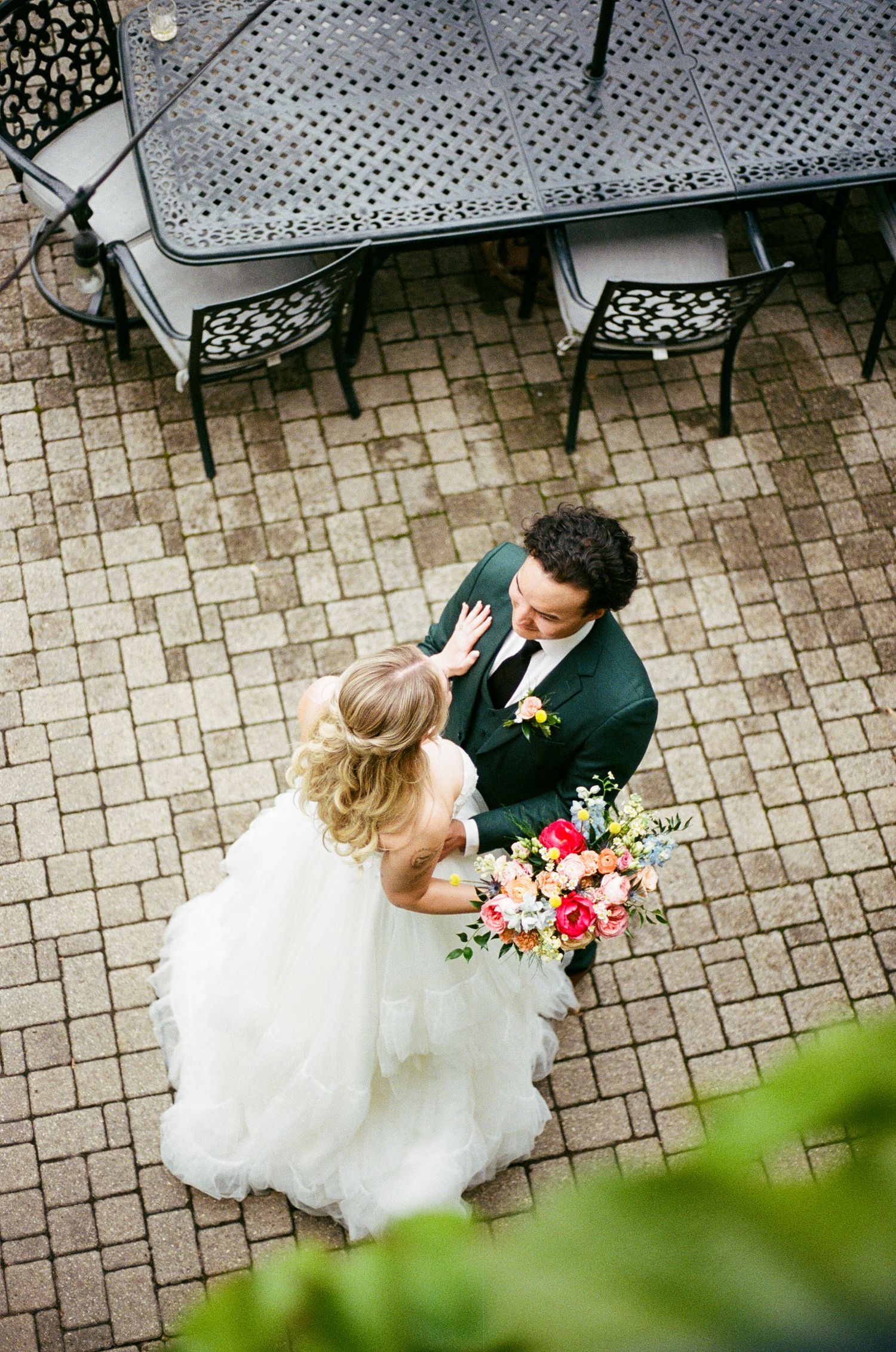 A joyful wedding moment on an urban street with a vibrant yellow and pink bouquet.