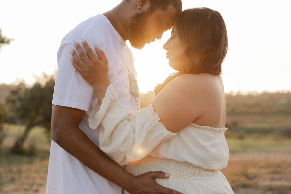 Intimate sunset portrait of couple sharing tender moment in white attire.