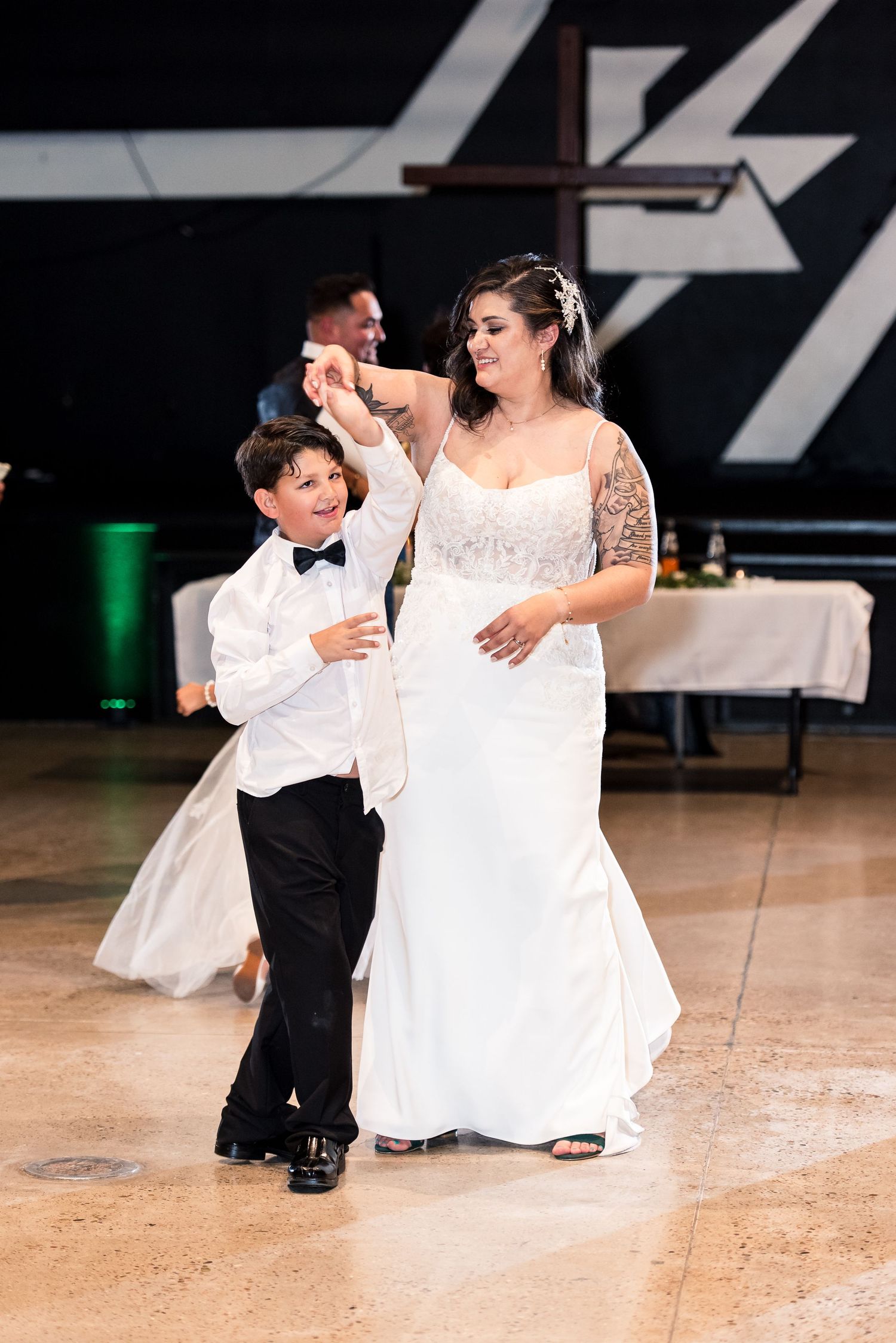 A wedding dance moment shared between a bride and young ring bearer on a dance floor.