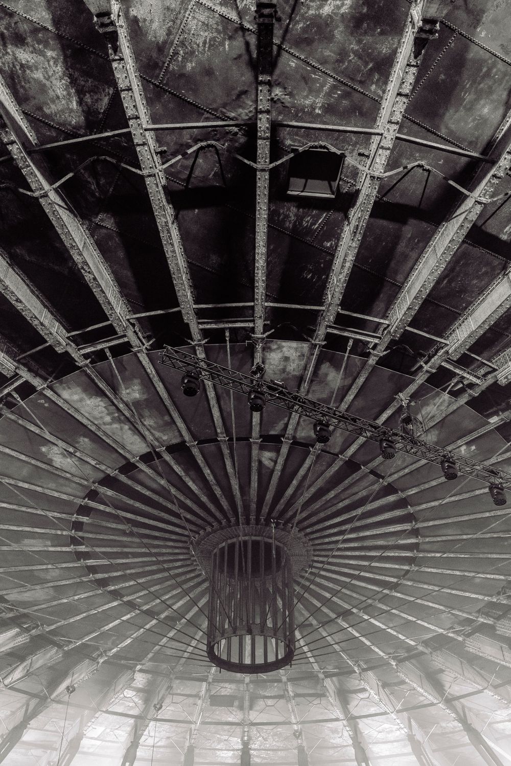 Industrial ceiling structure shown in black and white with radial metal beam pattern.