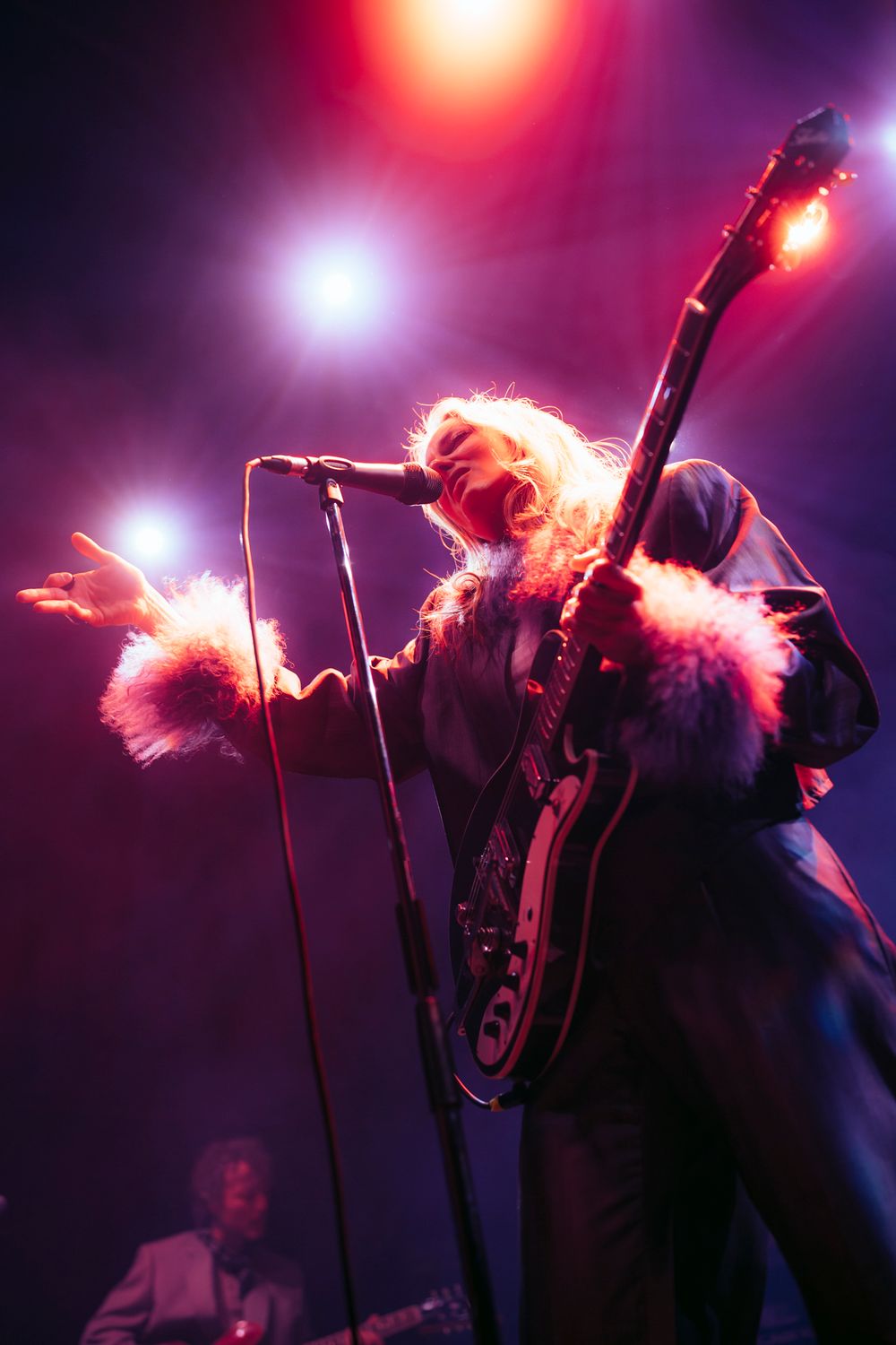 Dramatic concert silhouette with red and purple backlighting creating ethereal atmosphere.