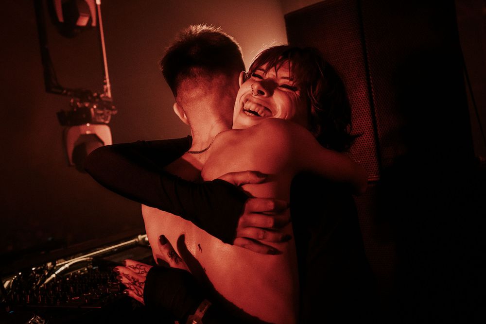 Energetic performance captured in moody red lighting on stage.