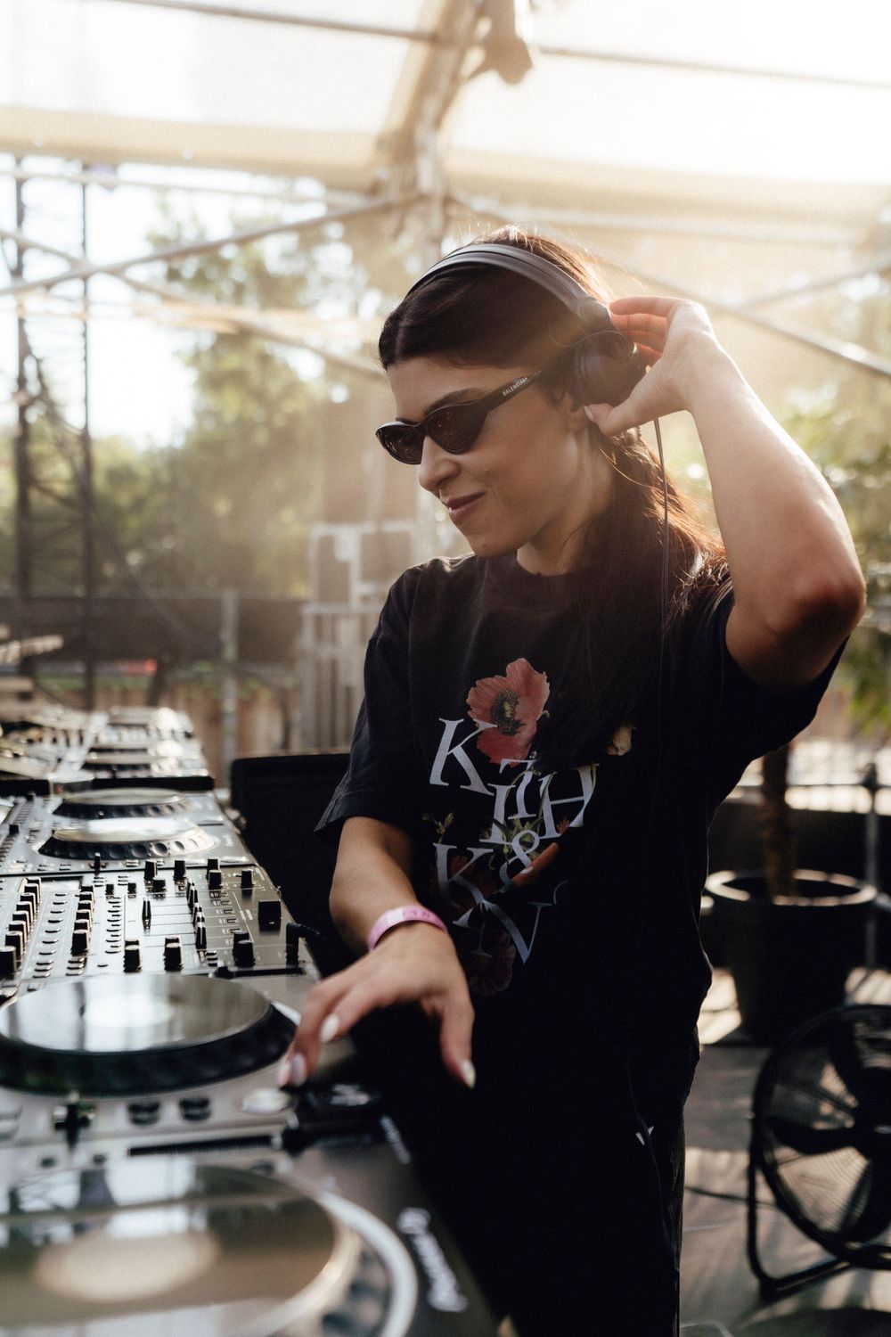DJ performing on stage with professional mixing equipment in golden sunset lighting.