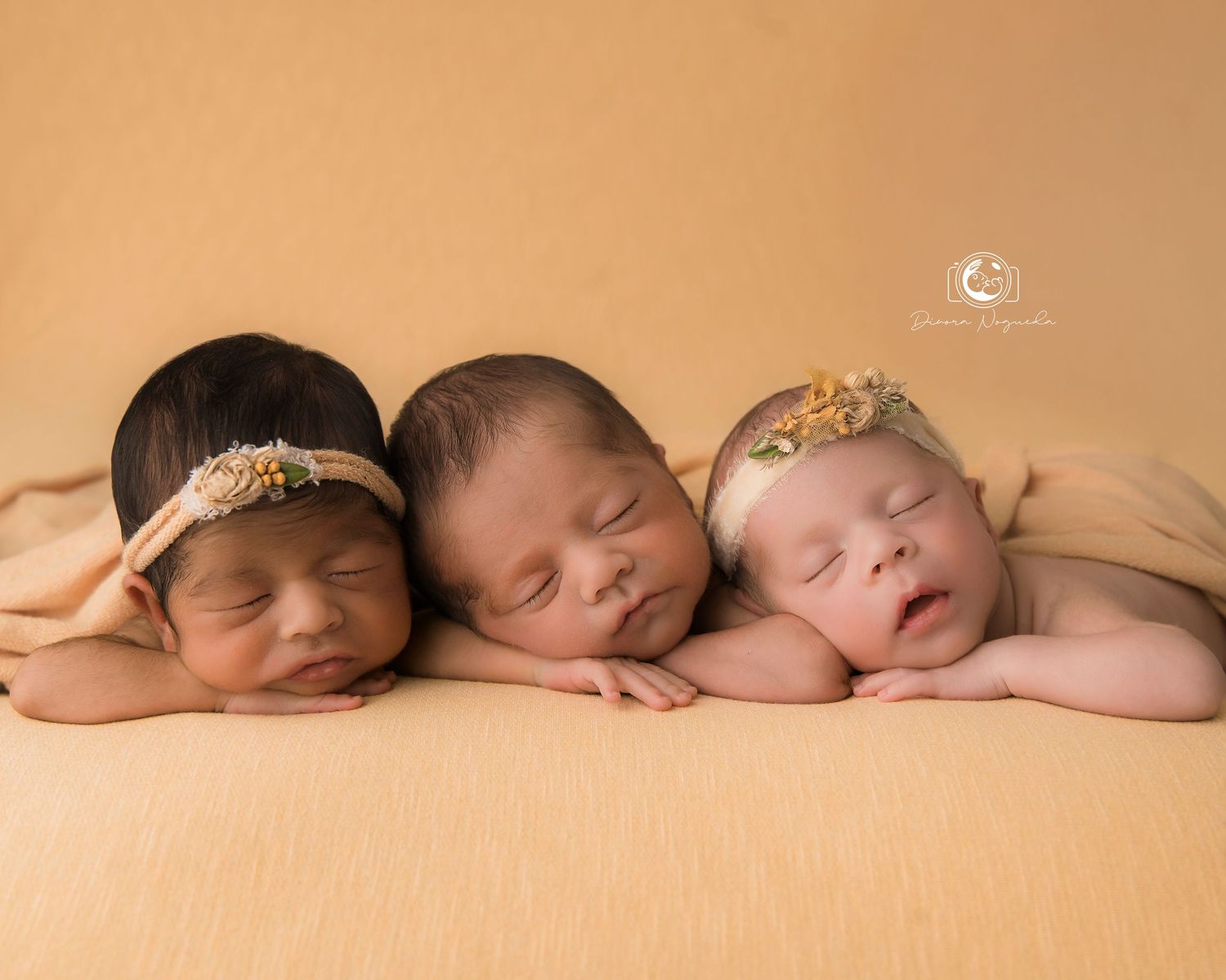 Peaceful sleeping newborn in peach wrap nestled in woven basket with yarn decorations.