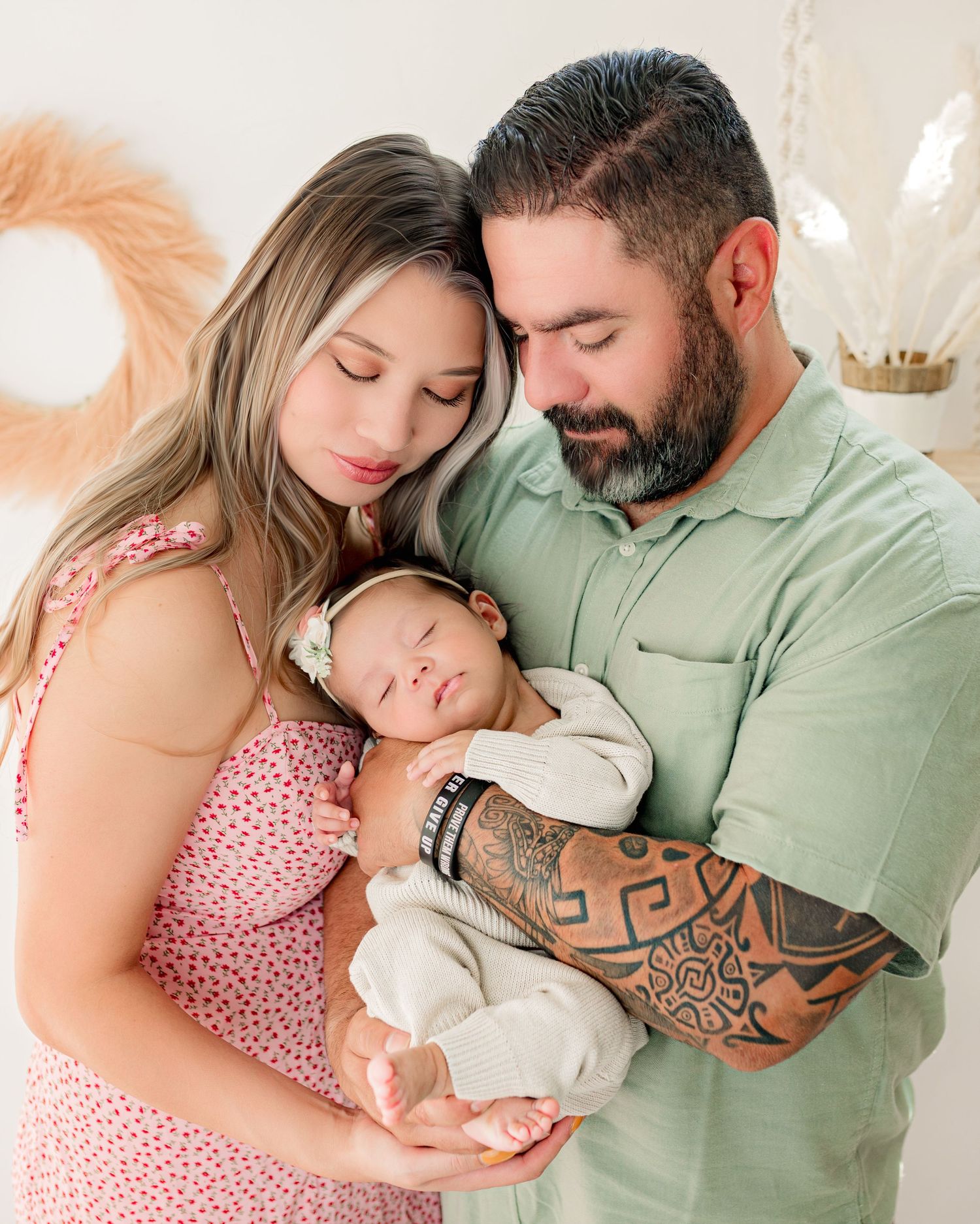 Family photo featuring sleeping newborn and cozy decor with dried flowers and soft lighting.