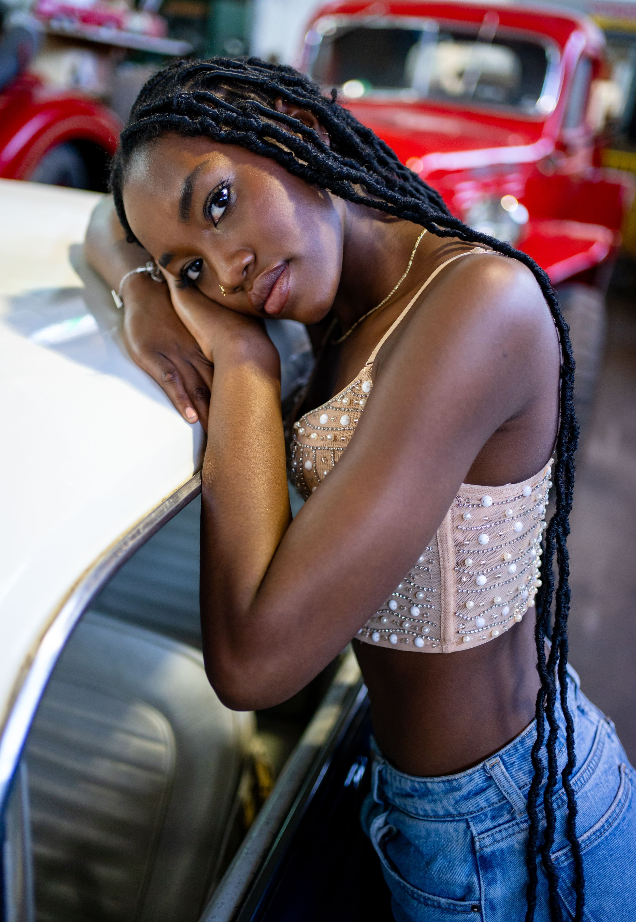 Fashionable portrait at vintage car show with red automobile in background.