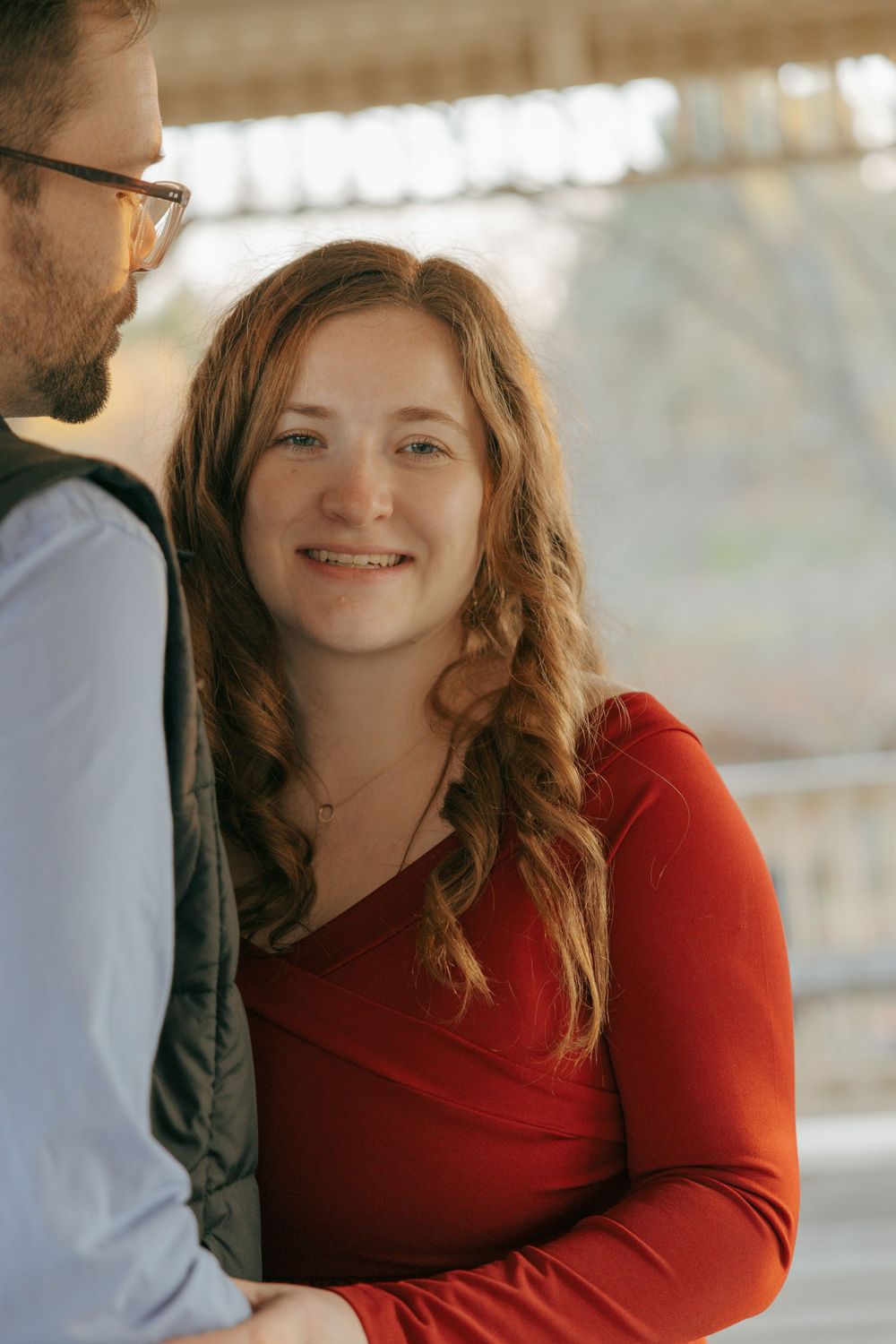 Intimate maternity portrait of couple with woman in red dress smiling warmly.