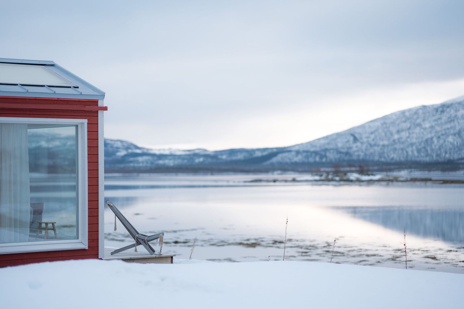 hotel norwegian wild cabane rouge en bord de lac en hiver, senja norvège