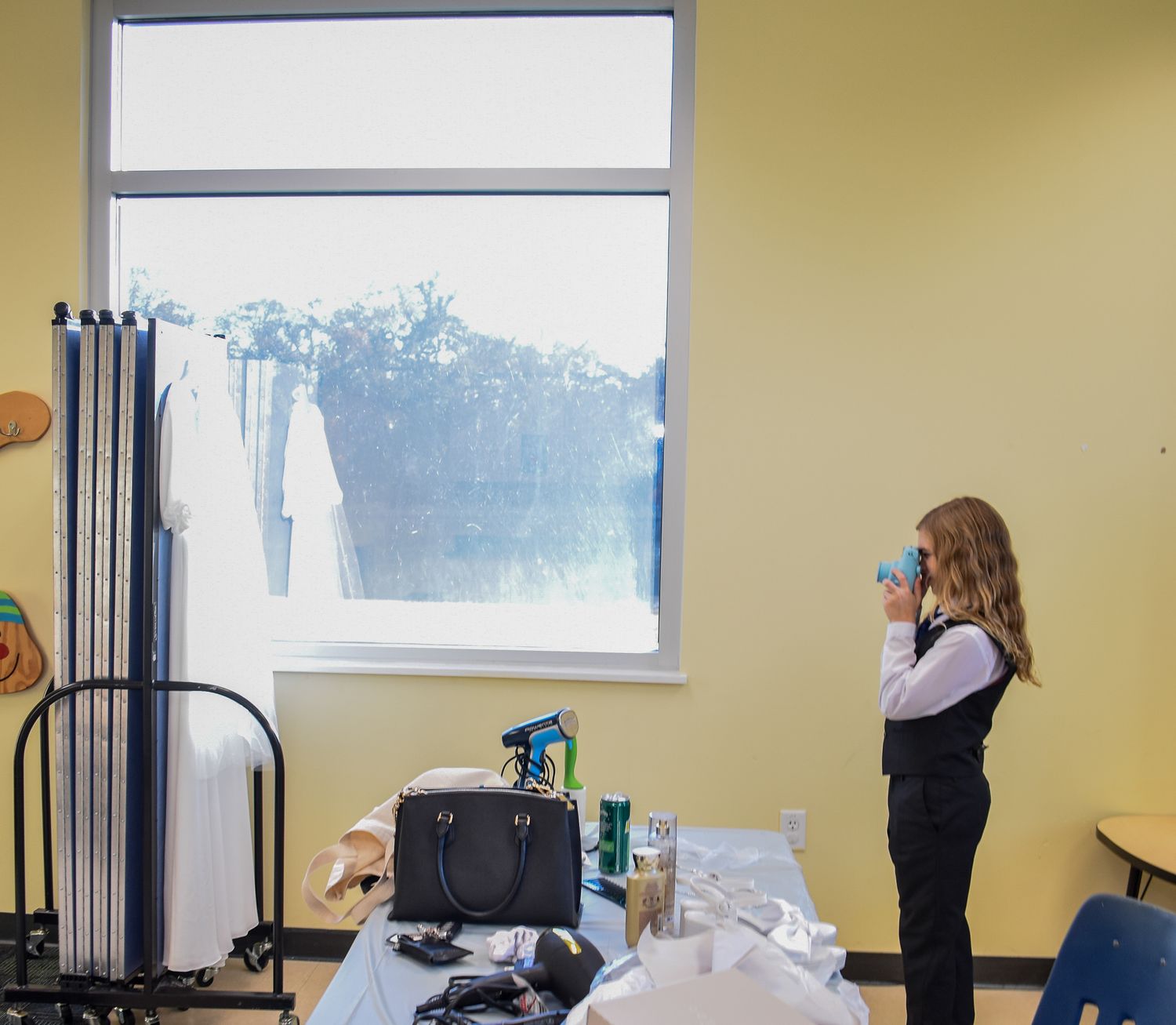 A preparation room setting with yellow walls and a window, showing dress fitting preparation items and equipment.