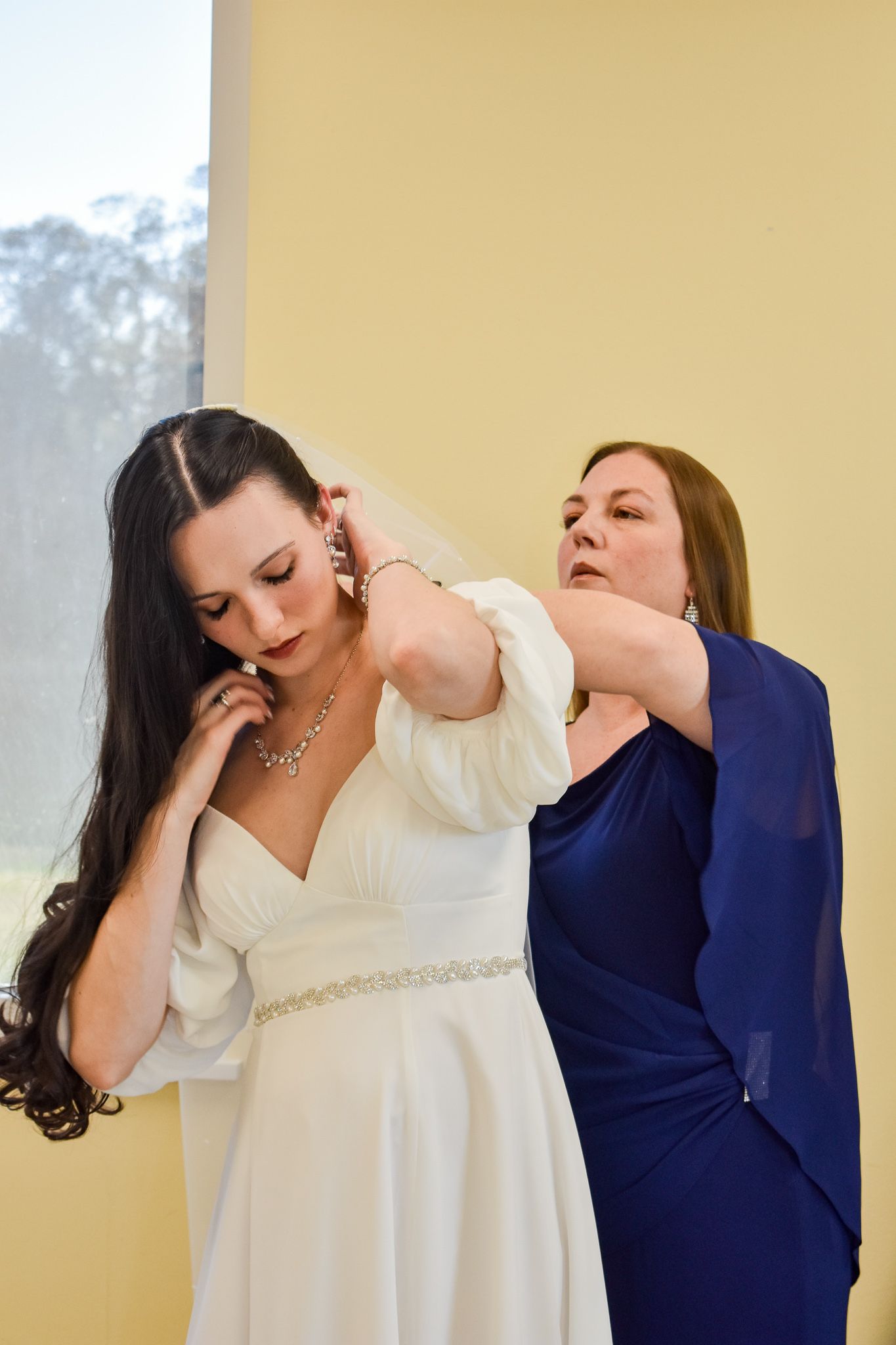 Wedding dress fitting showing jewelry and final adjustments being made.