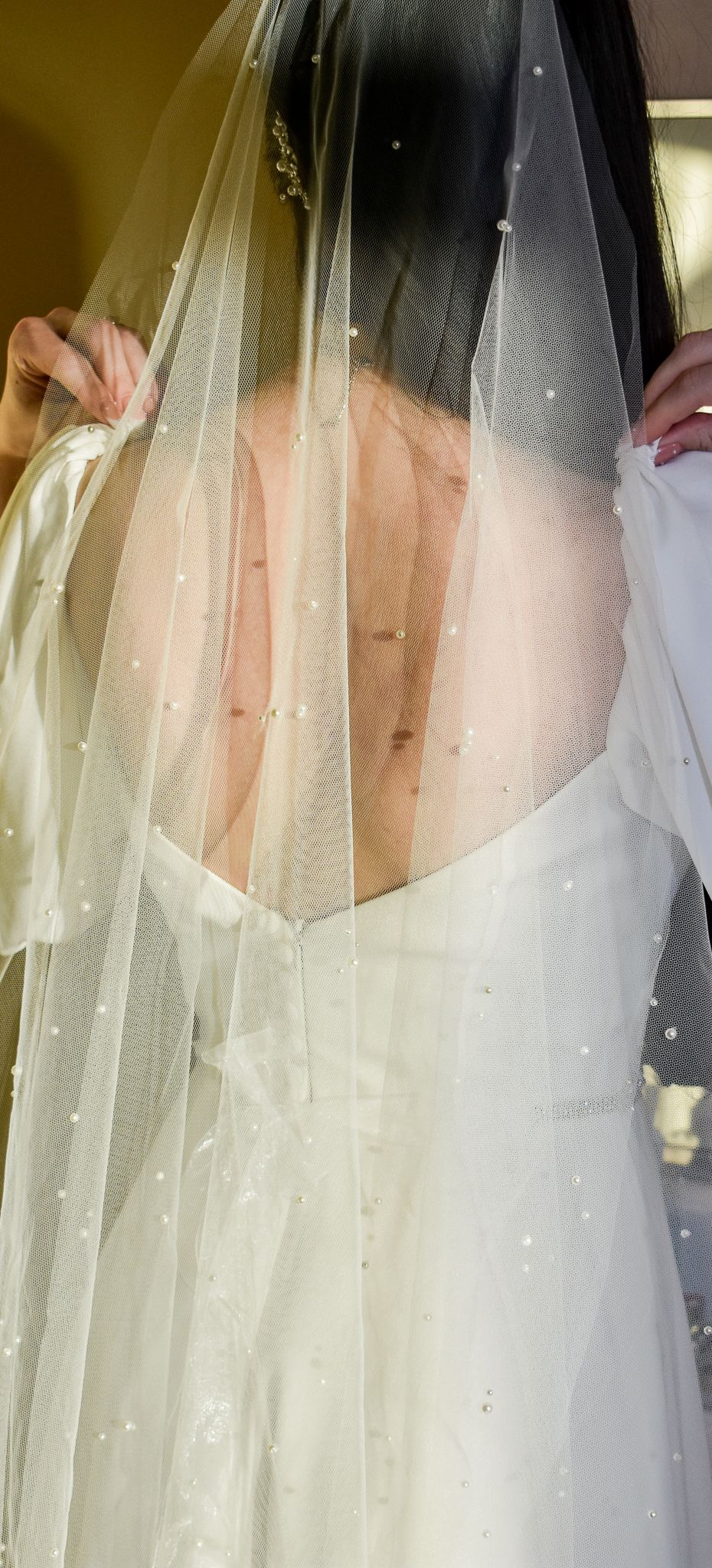 Detail shot of sparkly wedding veil and white dress bodice.