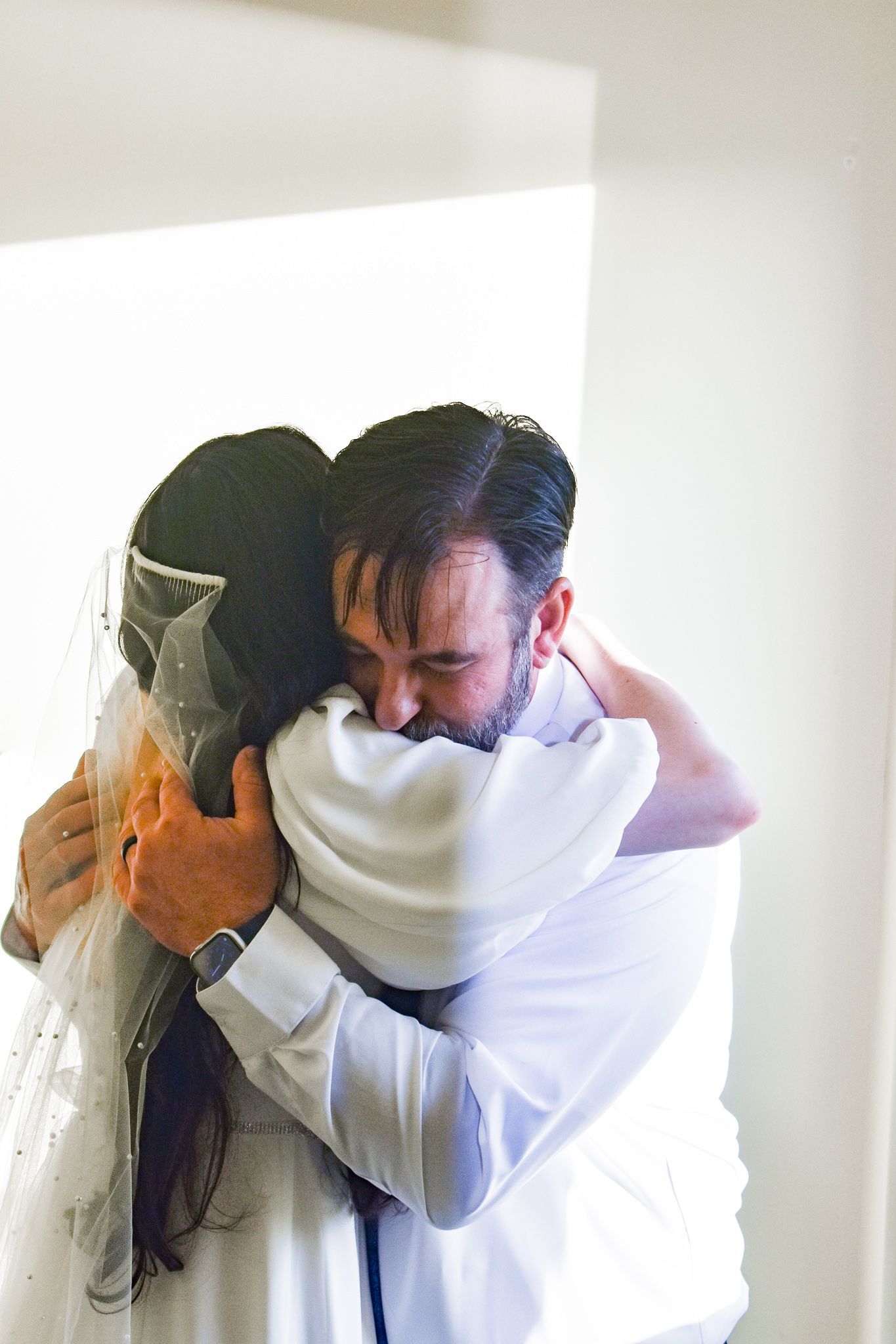 An emotional moment captured as a couple shares a tight embrace at their wedding ceremony.