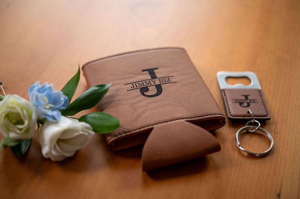 Personalized leather wedding gifts including monogrammed wallet and bottle opener keychain with flowers.