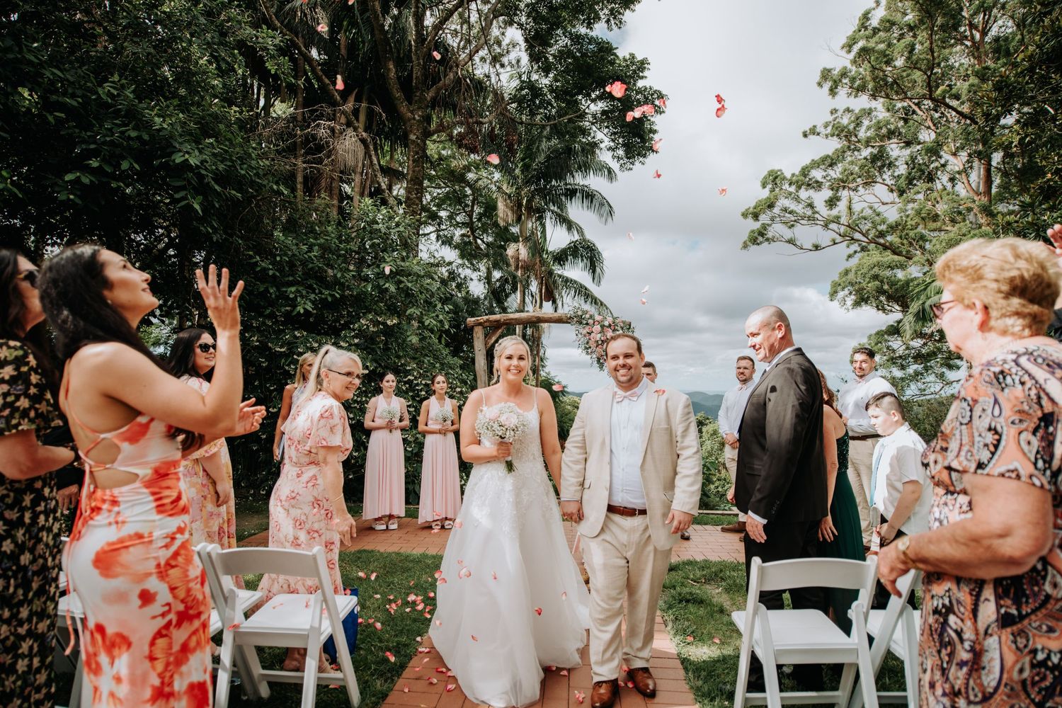 Wedding celebration outdoors with guests tossing petals in a joyous moment.