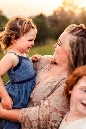 Three people share laughter and embraces in a sun-drenched field.