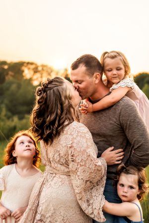 Family embraces in a close group hug during sunset in nature.