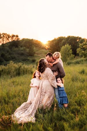 Family shares intimate moment together in golden sunlit field.