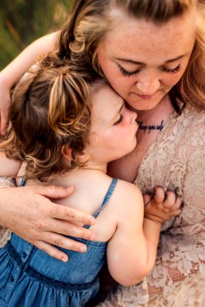 Tender moment between mother and child embracing in evening sunlight.