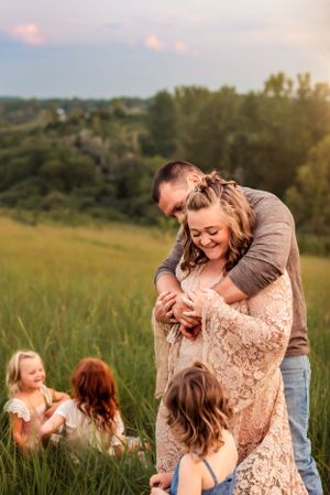 A family shares a joyful moment together in a sunlit meadow during golden hour.