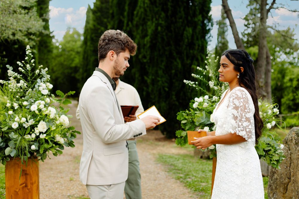 Garden wedding ceremony setup with cypress trees and white floral arrangements creating a romantic atmosphere.