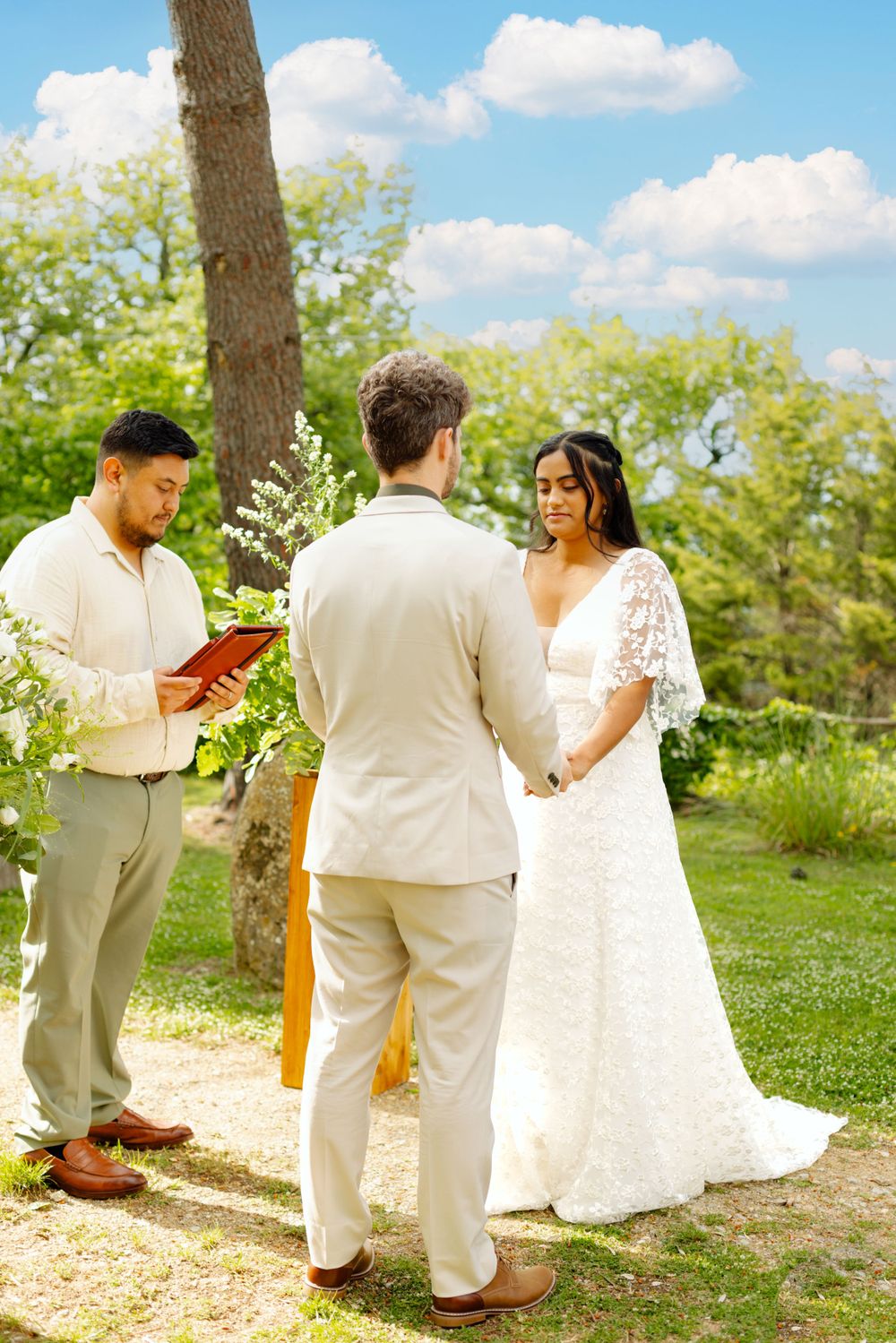 Elegant outdoor wedding ceremony setup with white chairs and natural decor against a lush garden backdrop.