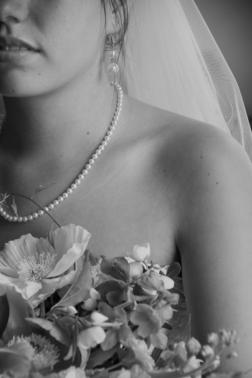 Elegant bride wearing pearl necklace and veil with delicate floral bouquet in black and white. Historic venue wedding photographer NC