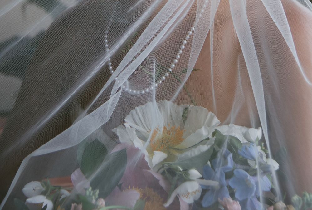 Dreamy bridal portrait showing pearl necklace, veil and bouquet details in soft focus. Historic venue wedding photographer North Carolina