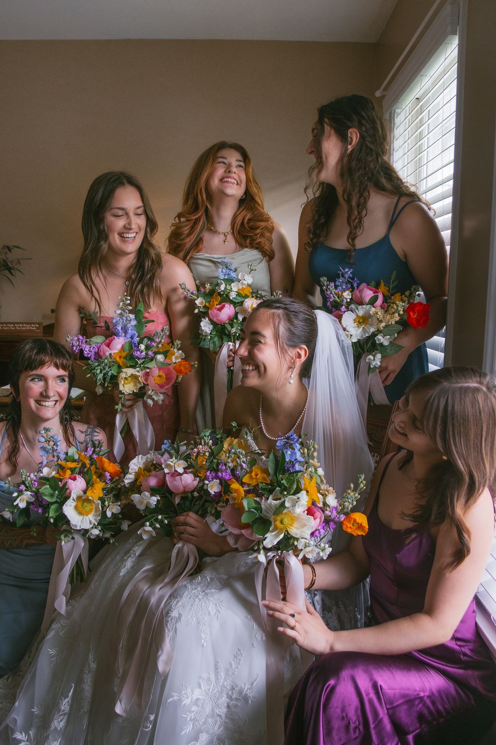 Wedding party in purple dresses gathered joyfully with colorful floral bouquets. Historic venue wedding photographer North Carolina