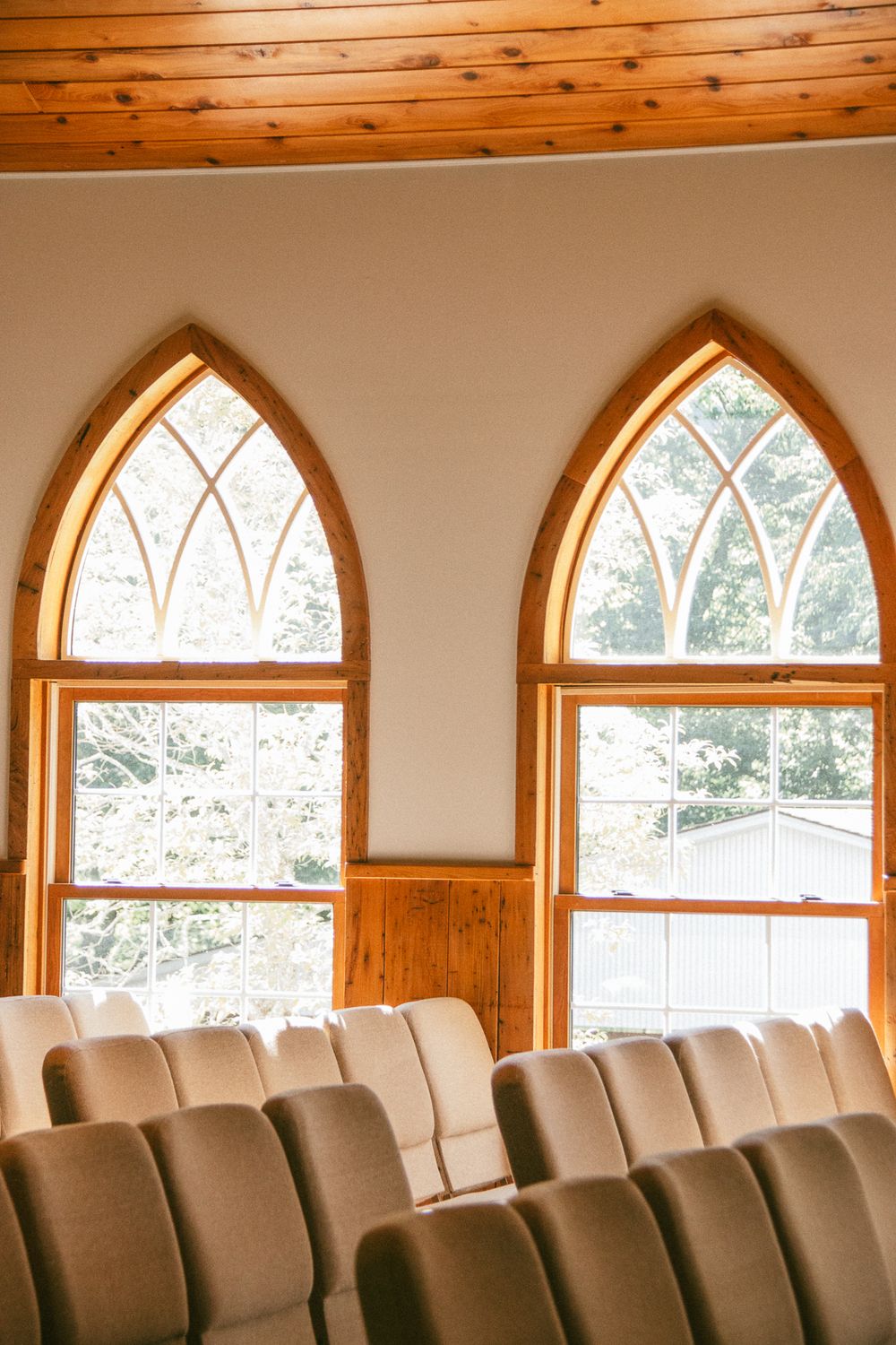 Row of arched windows with wooden trim in a church or chapel setting. Historic venue wedding photographer North Carolina