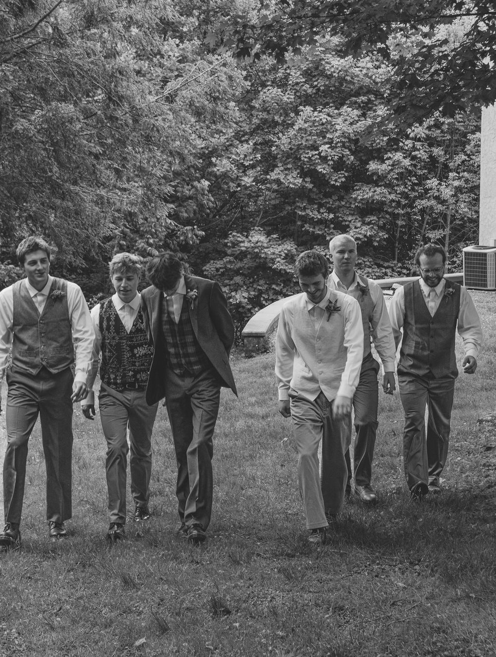 Black and white photo of wedding party lined up outdoors in casual poses. Historic venue wedding photographer North Carolina