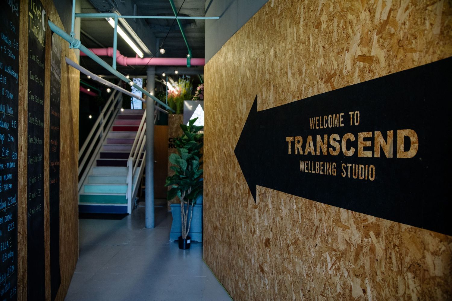 Dark hallway with stairs leading to Transcend wellness studio indicated by directional signage.