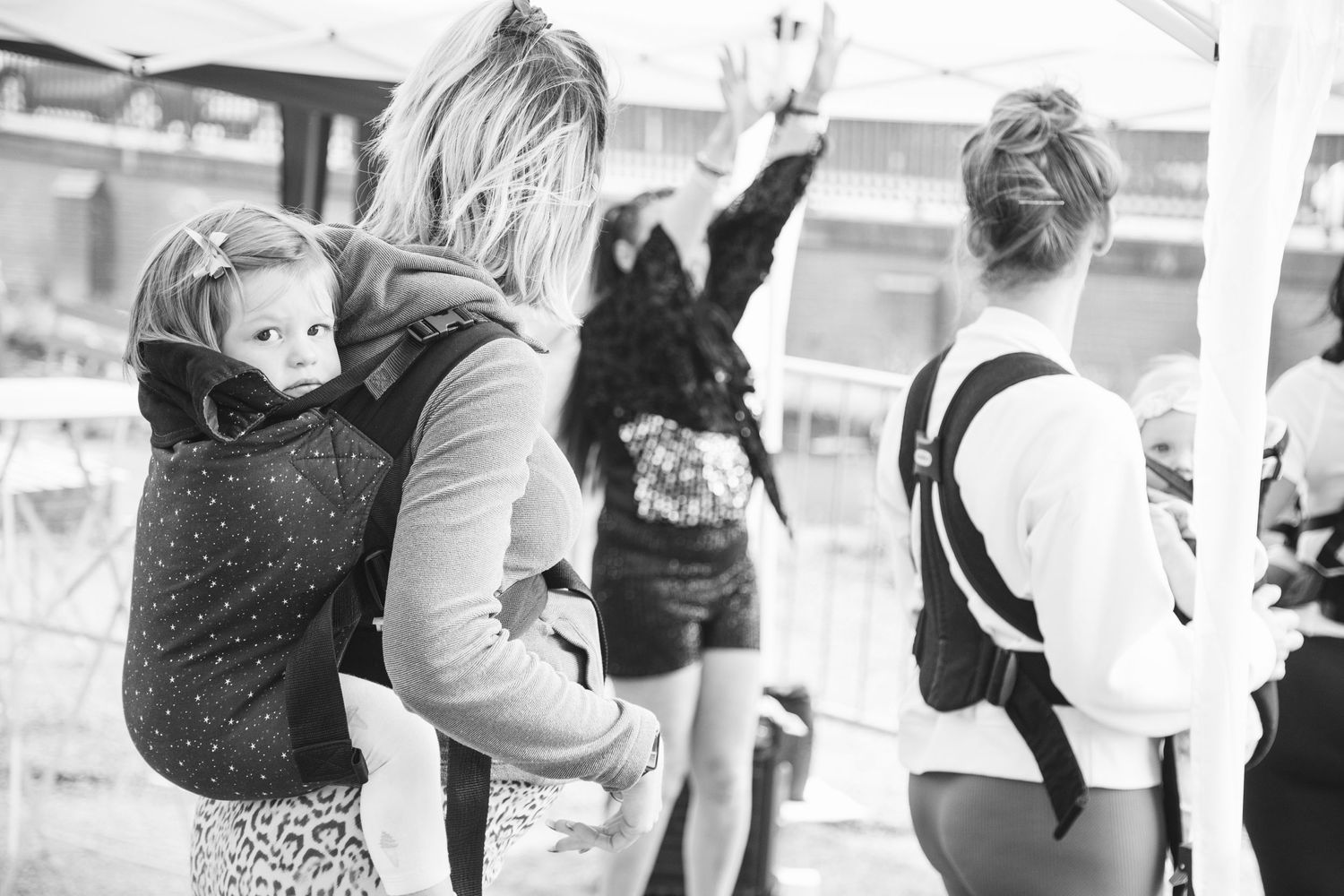 A group in casual attire dancing together at an indoor space captured in black and white.