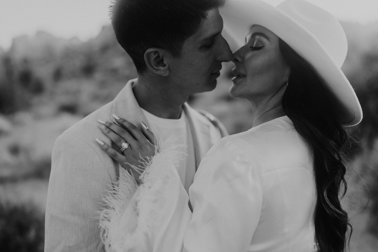 Black and white photo of a couple sharing a tender moment in a desert setting.