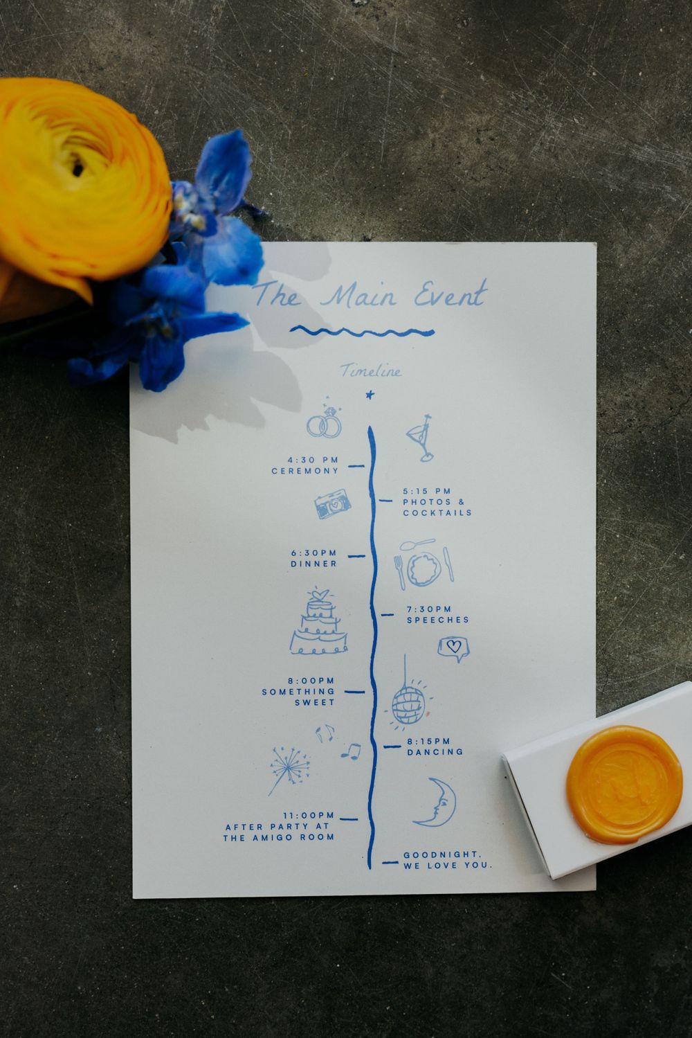 Wedding timeline schedule card decorated with yellow ranunculus and blue flowers on dark background.