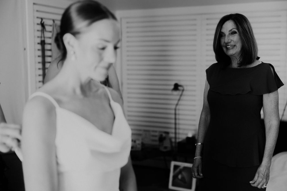 A black and white photo showing wedding preparations in a bedroom setting.