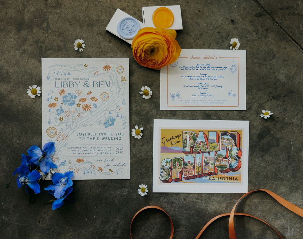 Wedding invitation suite with blue flowers, yellow ranunculus, and Palm Springs postcard.