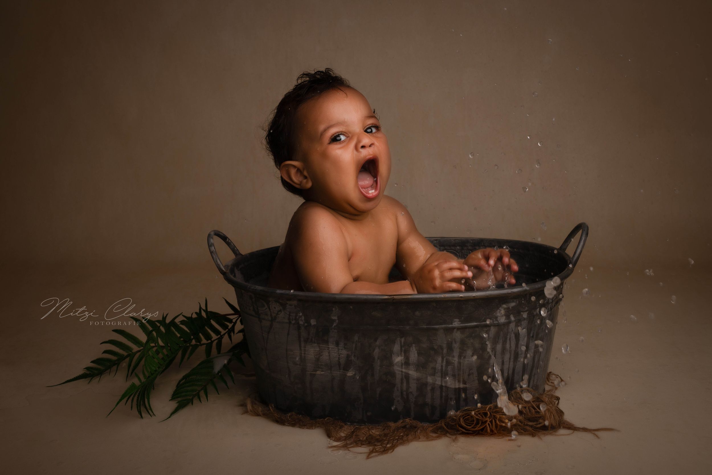 Portret van eenjarig jongetje spetterend in bad tijdens cakesmash sessie
