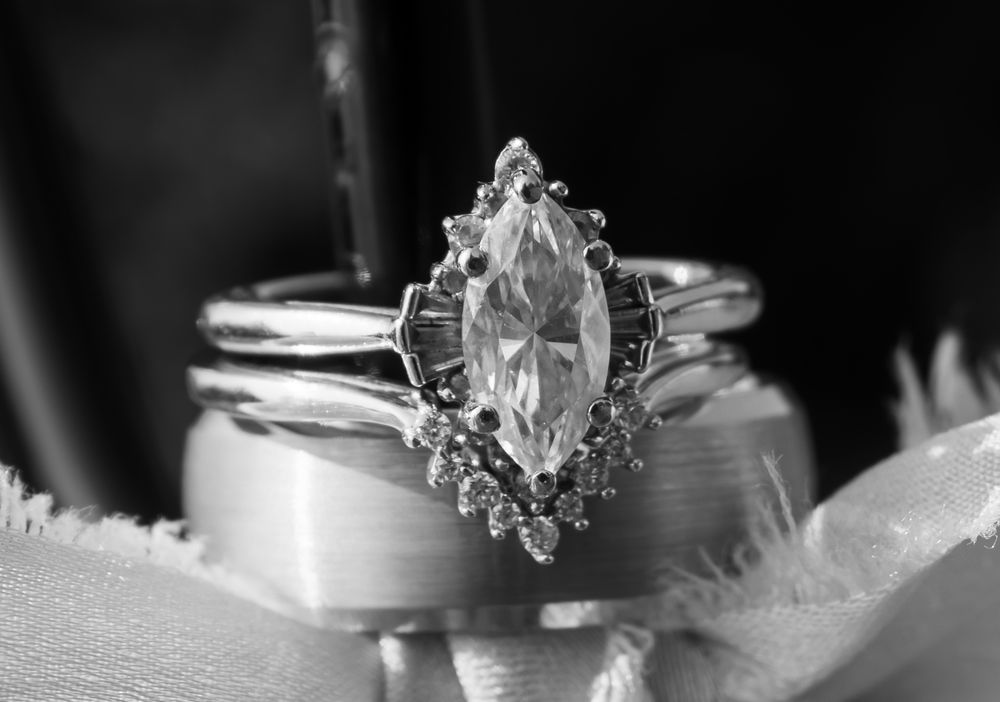 A series of black and white wedding details including rings, flowers, and table decor creates an elegant composition.