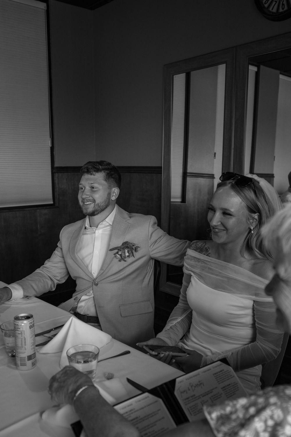 A couple dressed in formal attire shares a joyful moment while seated at a table during a special occasion.