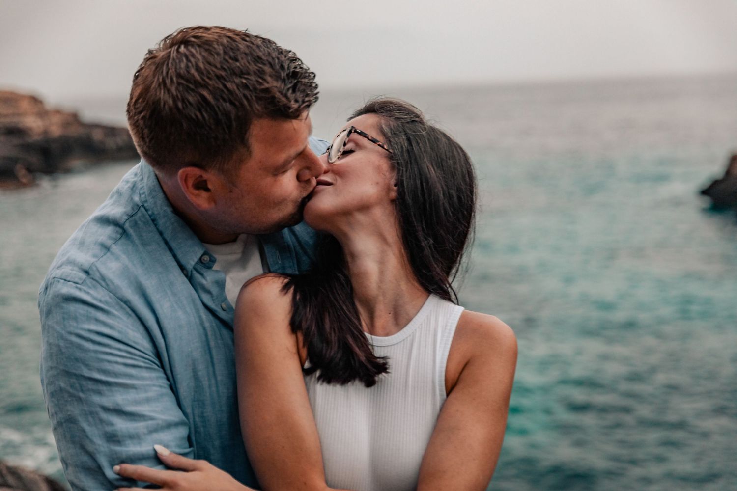 Romantic couple kissing by the Mediterranean sea during a Mallorca engagement photoshoot.