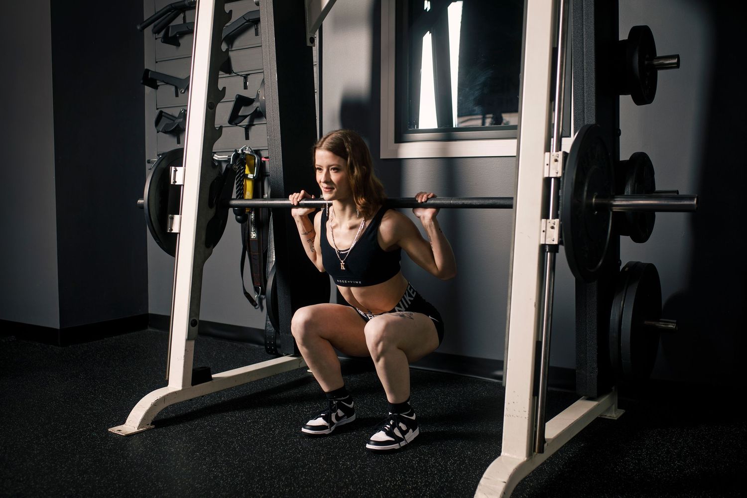 Person working out through a series of dynamic yoga or stretching poses in a dimly lit fitness studio space.