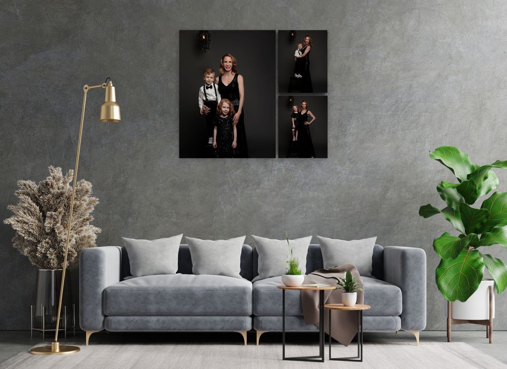 Modern living room with gray sofa, gold lamp, and framed photos on concrete wall.