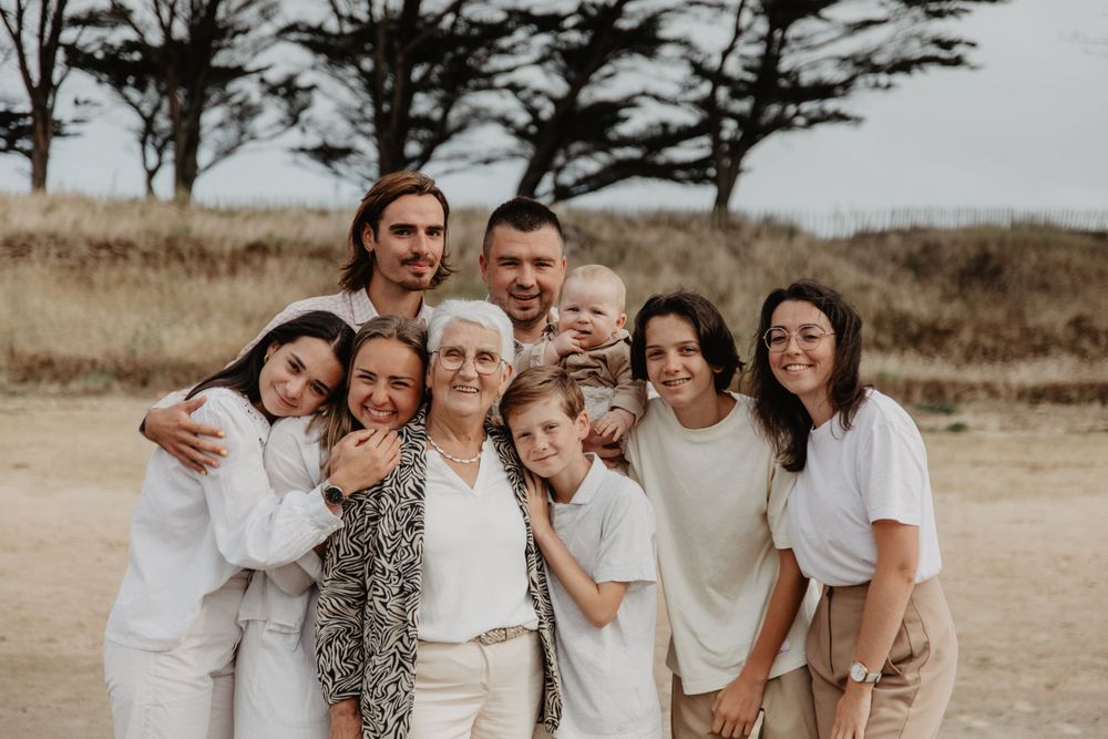 famille posent ensemble à l’extérieur avec des arbres en arrière-plan au coucher du soleil