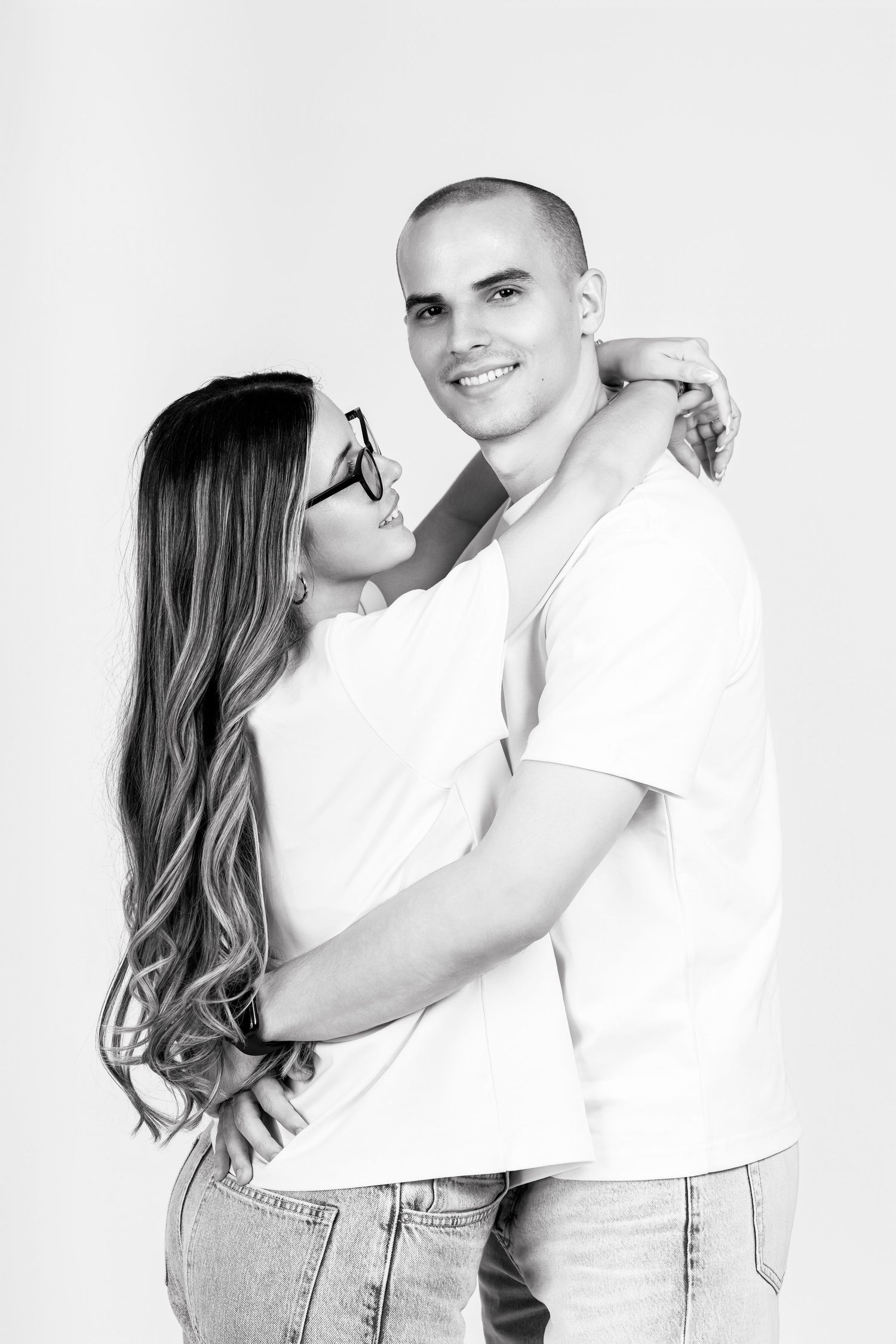 Black and white studio portraits of couple in casual white outfits.