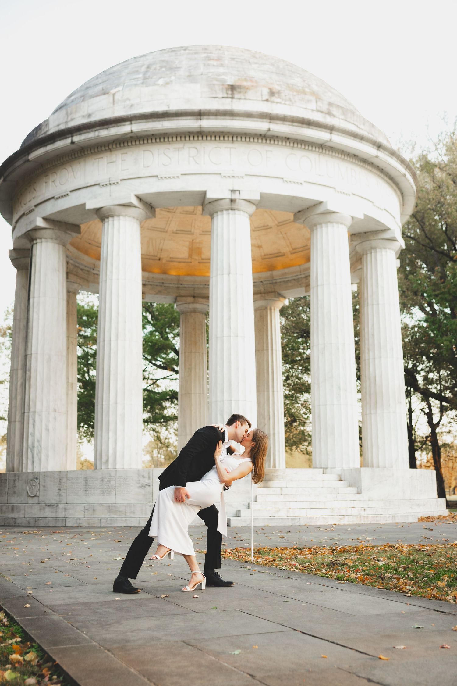 A couple shares a dance dip pose in front of the DC War Memorial.
