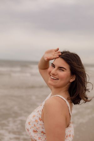Candid beach portraits showing someone in a floral top with wind-swept hair.