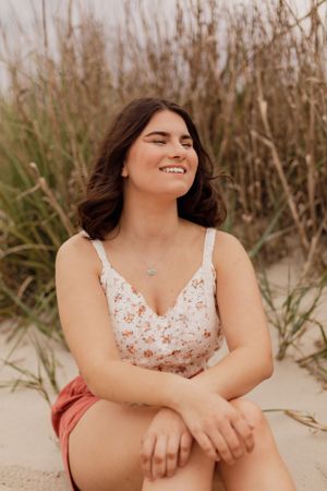 A joyful summer portrait featuring a floral crop top and coral shorts against tall beach grass.